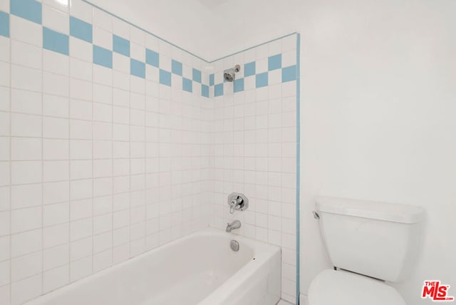 bathroom with toilet and tiled shower / bath