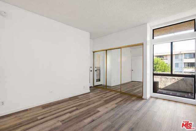 unfurnished bedroom featuring wood-type flooring, a textured ceiling, and a closet