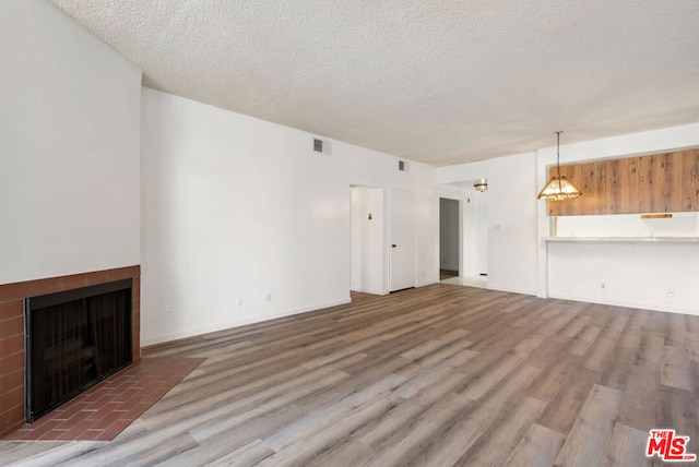 unfurnished living room featuring hardwood / wood-style floors, a textured ceiling, and an inviting chandelier