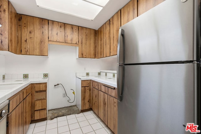 kitchen with light tile patterned floors, stainless steel appliances, and tile counters