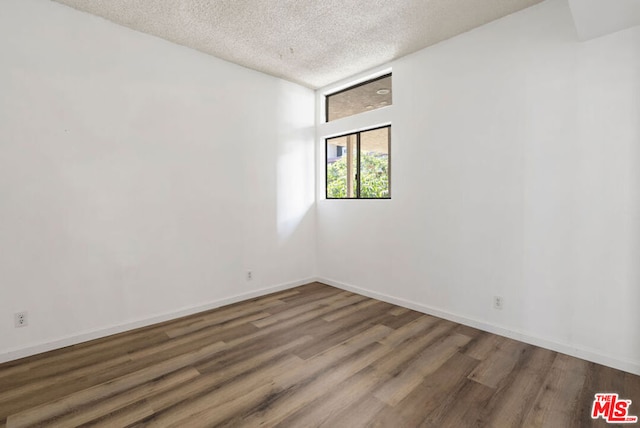 empty room with dark hardwood / wood-style flooring and a textured ceiling