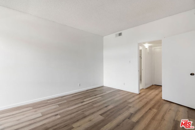 empty room featuring wood-type flooring and a textured ceiling