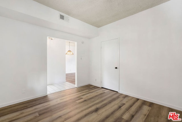 spare room with hardwood / wood-style floors and a textured ceiling