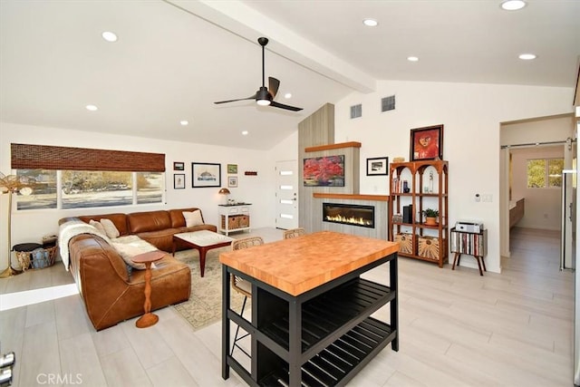 living room featuring vaulted ceiling with beams, a fireplace, and light wood-type flooring