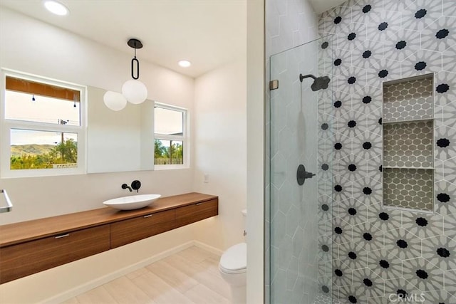 bathroom featuring a shower with door, vanity, and toilet