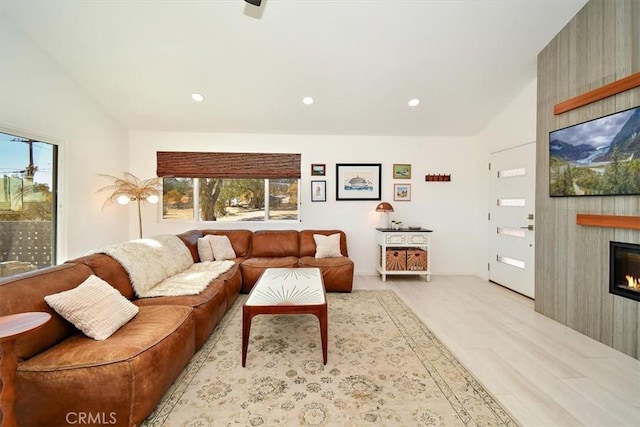 living room featuring light wood-type flooring, a fireplace, and vaulted ceiling