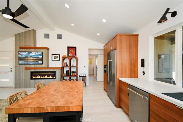 kitchen featuring light wood-type flooring, appliances with stainless steel finishes, vaulted ceiling with beams, and ceiling fan