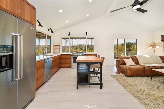 kitchen with high vaulted ceiling, light hardwood / wood-style flooring, ceiling fan, beamed ceiling, and stainless steel appliances