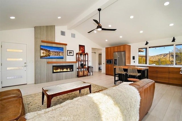 living room with lofted ceiling with beams, sink, ceiling fan, a fireplace, and light hardwood / wood-style floors