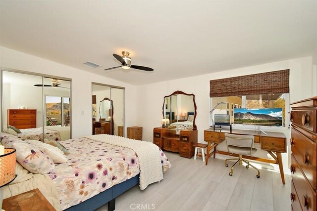 bedroom featuring ceiling fan, two closets, and light hardwood / wood-style flooring