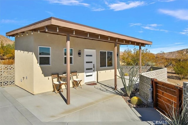 back of property with a mountain view and a patio