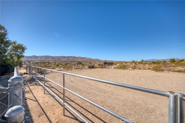 view of yard with an enclosed area, a rural view, and a mountain view