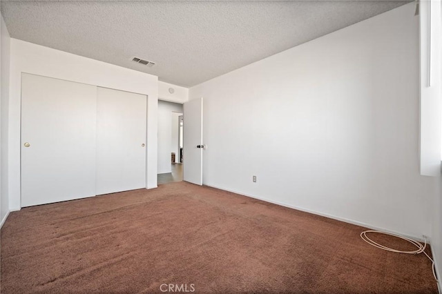 unfurnished bedroom with a closet, carpet, and a textured ceiling