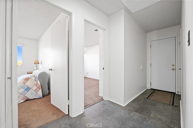 corridor featuring dark carpet and a textured ceiling