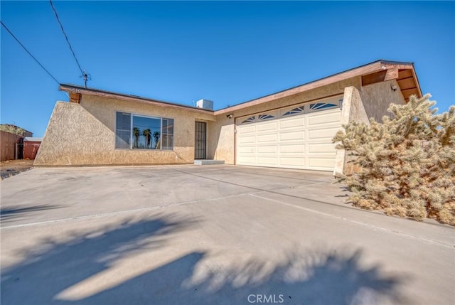 view of front facade featuring a garage, concrete driveway, and stucco siding