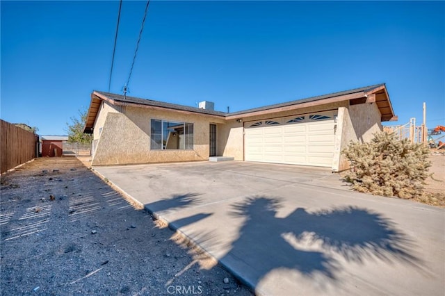 view of front facade with driveway, a garage, fence, and stucco siding