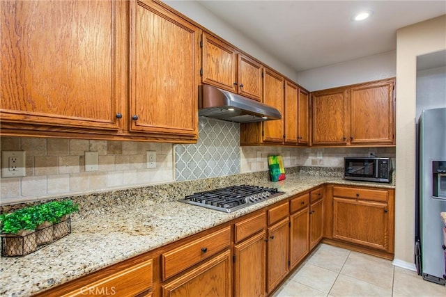 kitchen with light stone countertops, appliances with stainless steel finishes, tasteful backsplash, and light tile patterned floors