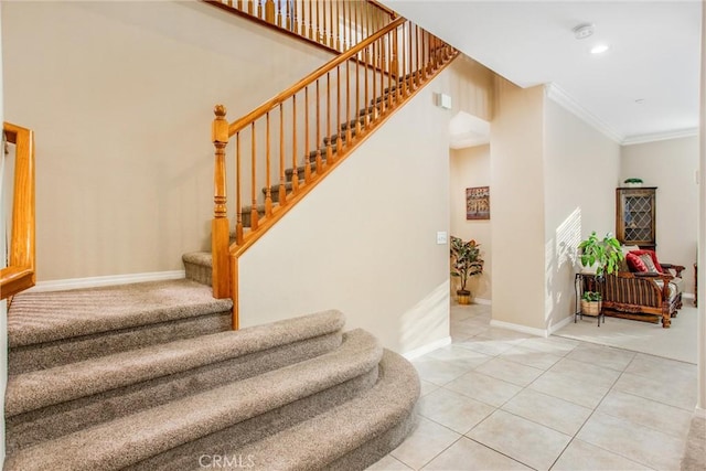 stairway with tile patterned floors, a high ceiling, and ornamental molding