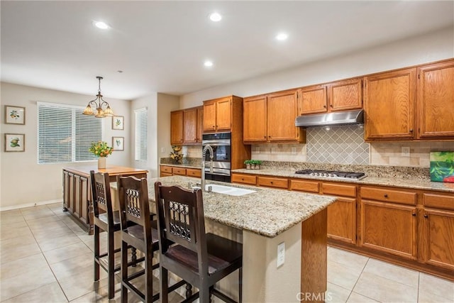 kitchen with hanging light fixtures, a notable chandelier, an island with sink, a breakfast bar area, and appliances with stainless steel finishes