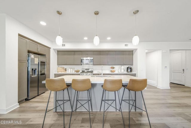 kitchen with pendant lighting, a large island, light wood-type flooring, and appliances with stainless steel finishes