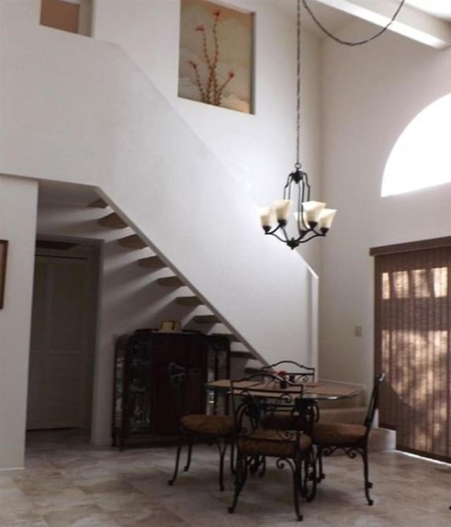 dining area with a towering ceiling and an inviting chandelier