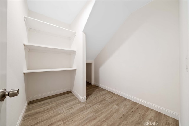 spacious closet with light wood-type flooring and vaulted ceiling