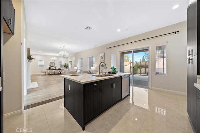 kitchen with stainless steel dishwasher, sink, a notable chandelier, hanging light fixtures, and an island with sink