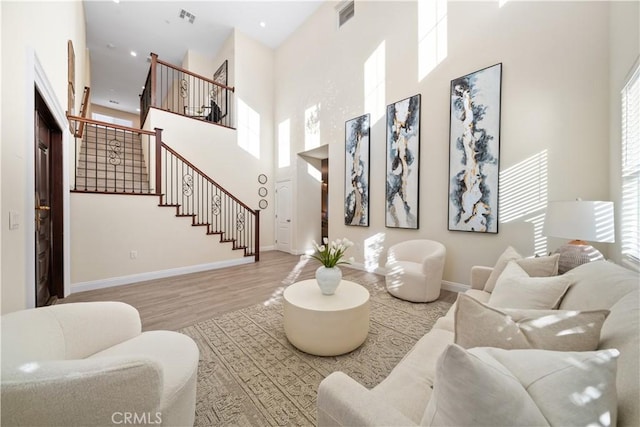 living room with light hardwood / wood-style floors and a towering ceiling