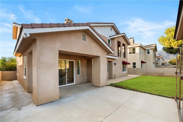 rear view of house featuring a lawn and a patio