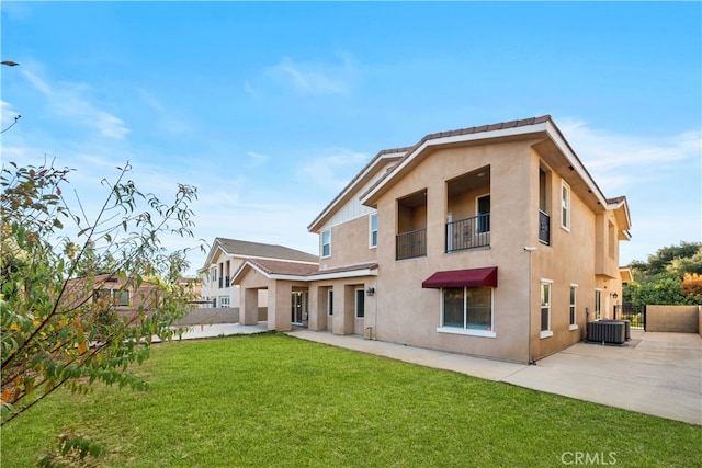 rear view of house with a lawn, central AC unit, a balcony, and a patio area