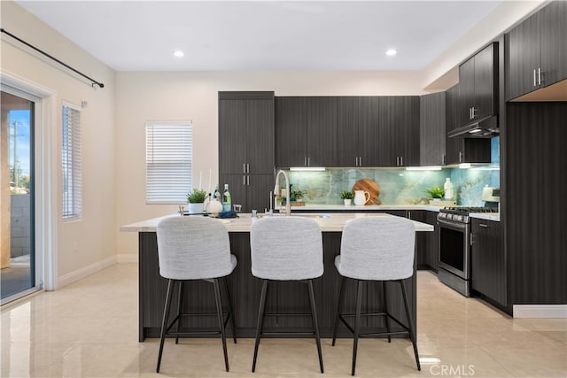 kitchen featuring sink, backsplash, a breakfast bar area, and stainless steel range with gas stovetop