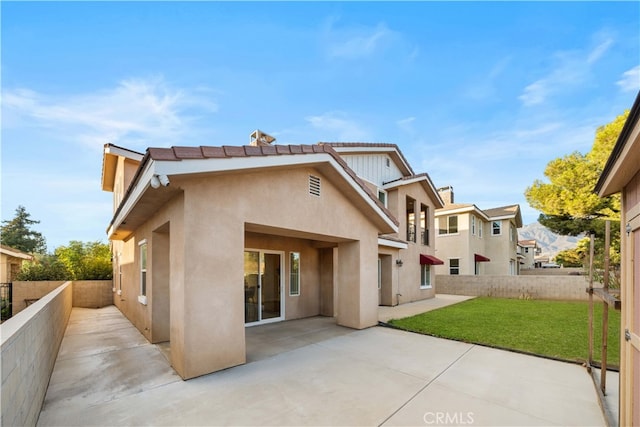 back of property with a lawn and a patio