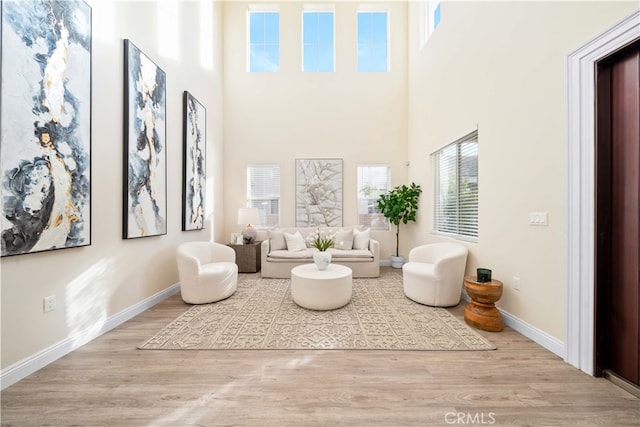 sitting room with light hardwood / wood-style floors and a high ceiling