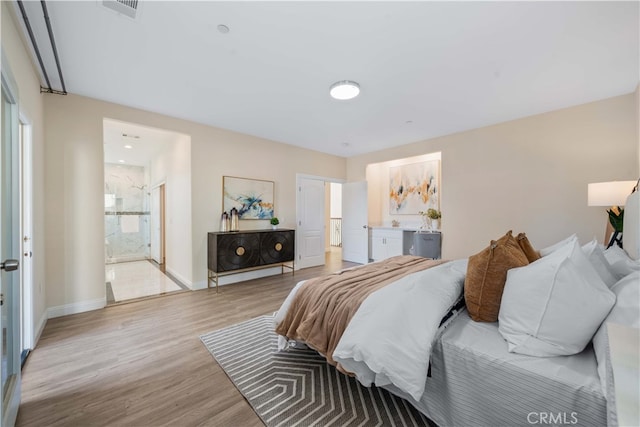 bedroom featuring ensuite bathroom and light hardwood / wood-style floors