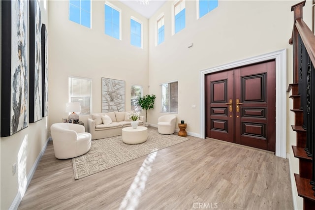 living room featuring a towering ceiling and light hardwood / wood-style floors