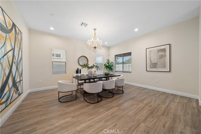 dining area with light hardwood / wood-style flooring and an inviting chandelier