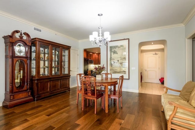 dining room with dark wood-type flooring, a chandelier, and ornamental molding