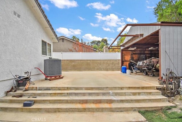 view of patio with a storage unit and central AC unit