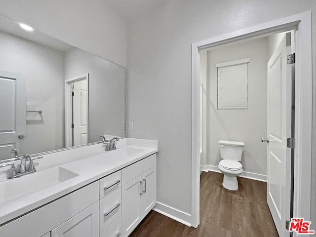 bathroom with toilet, vanity, and hardwood / wood-style flooring