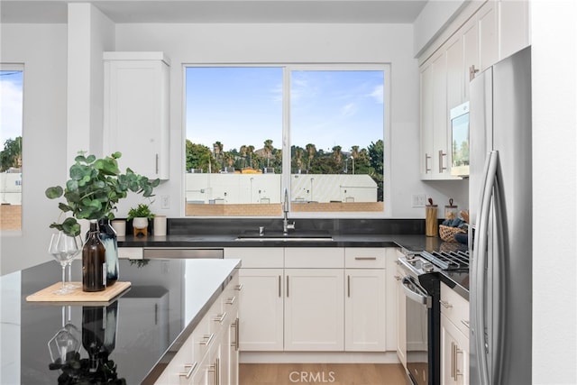 kitchen with a wealth of natural light, white cabinetry, sink, and appliances with stainless steel finishes