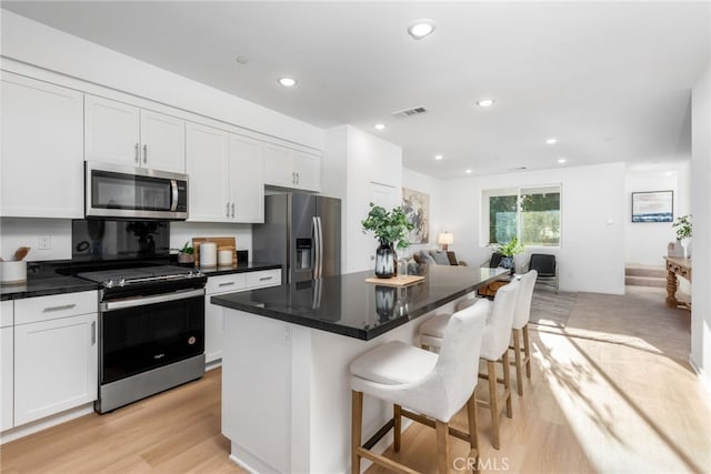 kitchen featuring a kitchen bar, white cabinets, a kitchen island, and stainless steel appliances