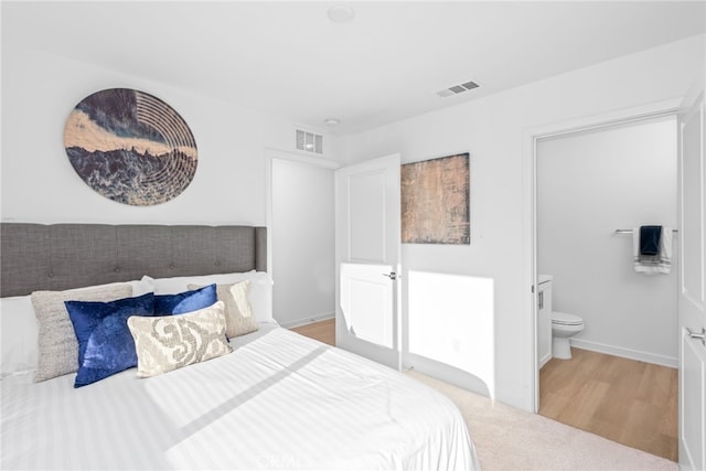 bedroom with light hardwood / wood-style floors and connected bathroom