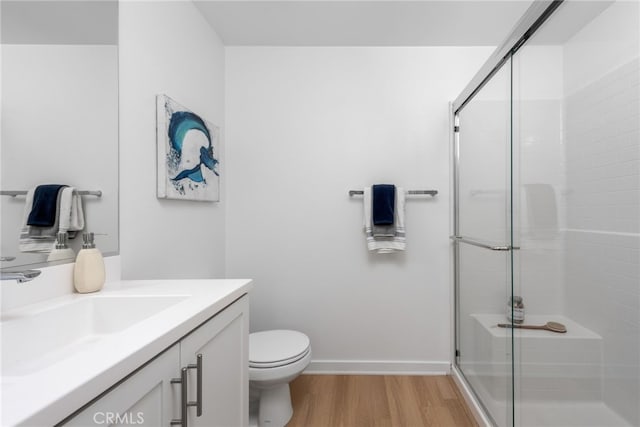 bathroom with wood-type flooring, vanity, toilet, and a shower with door