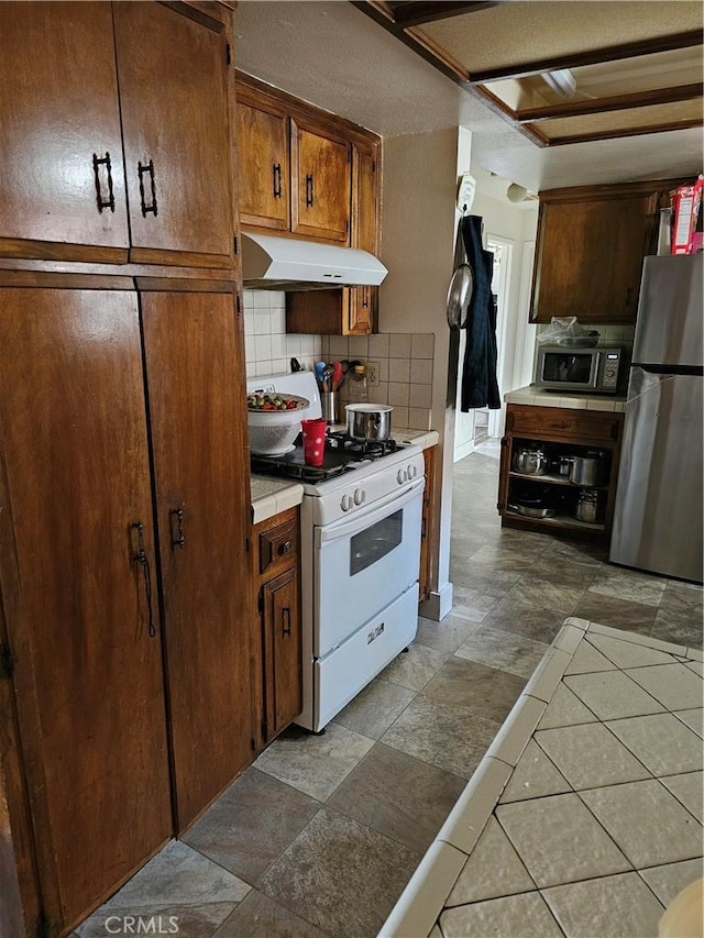 kitchen with tile countertops, decorative backsplash, and stainless steel appliances