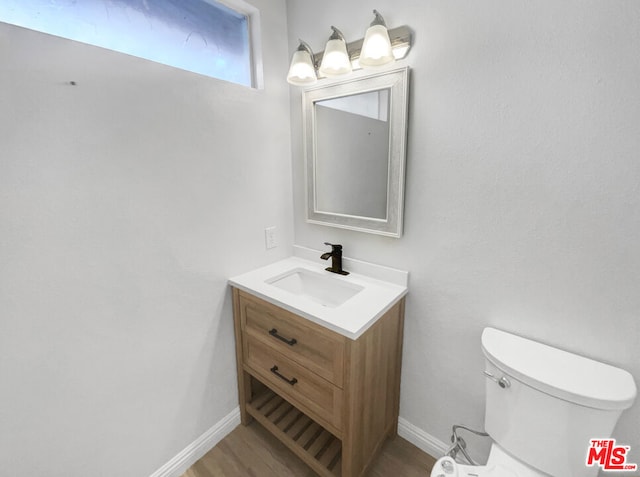 bathroom with hardwood / wood-style floors, vanity, and toilet