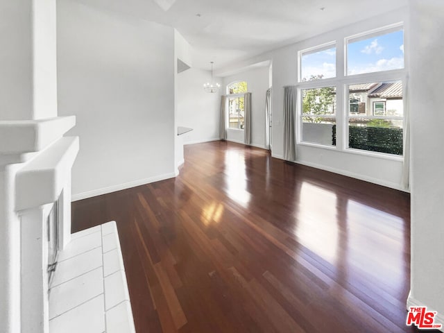 unfurnished living room featuring dark wood-type flooring and a notable chandelier