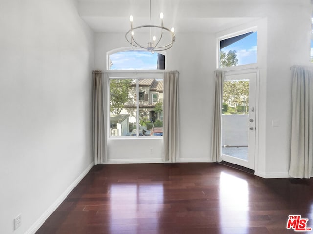 entrance foyer with a chandelier, a wealth of natural light, and dark wood-type flooring