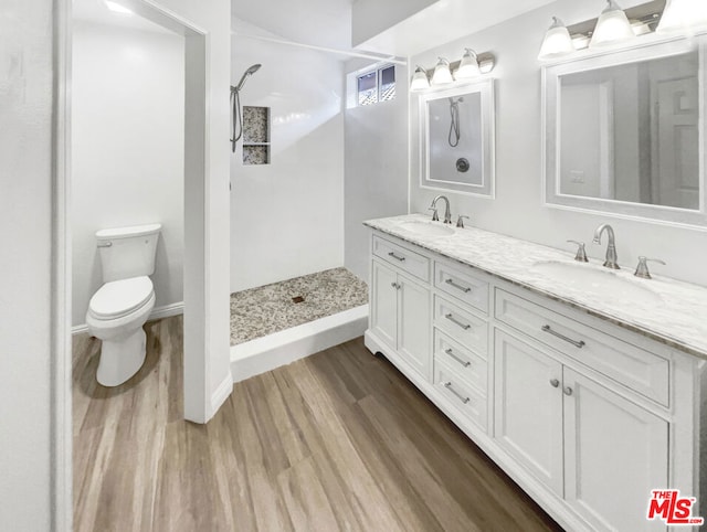 bathroom with a shower, hardwood / wood-style floors, vanity, and toilet