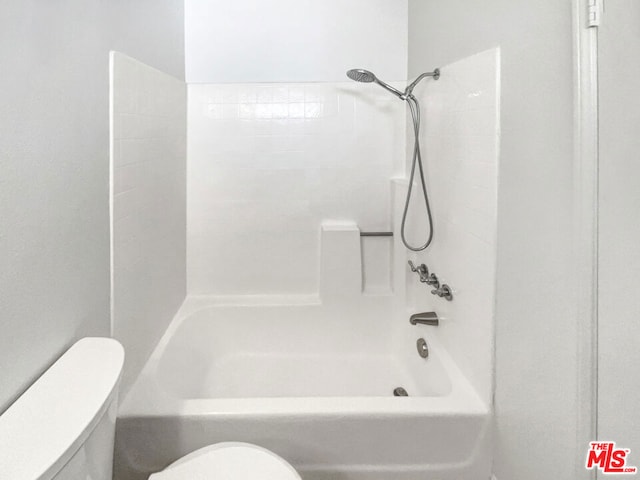 bathroom featuring toilet and tiled shower / bath