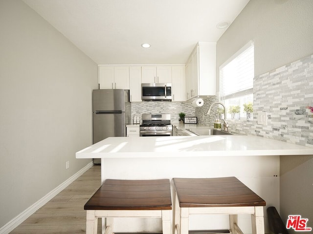 kitchen with kitchen peninsula, tasteful backsplash, stainless steel appliances, sink, and a breakfast bar area